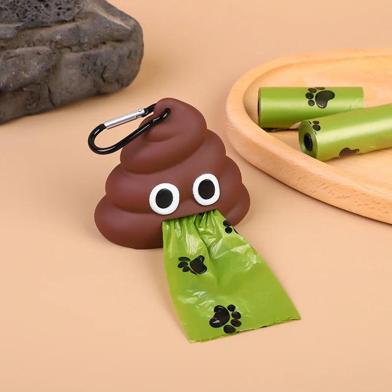 Brown poop emoji bag dispensing a green poop bag, with two extra rolls on a wooden tray and flowers in the background.