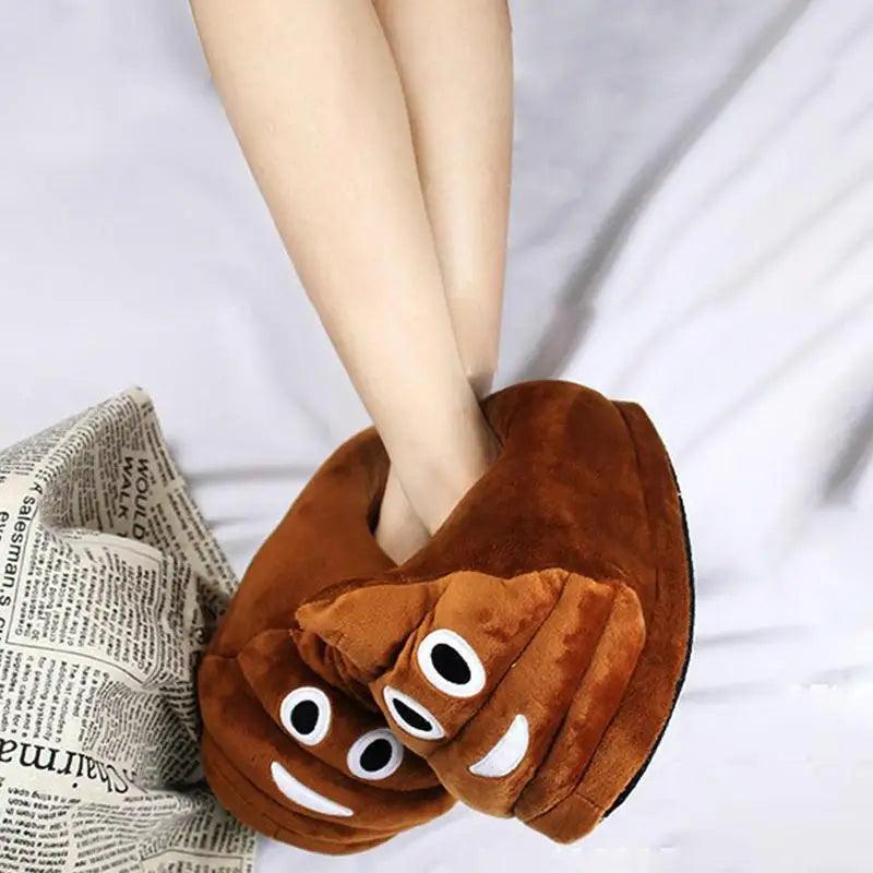 Person wearing brown poop emoji slippers with smiling faces on a white fluffy surface.