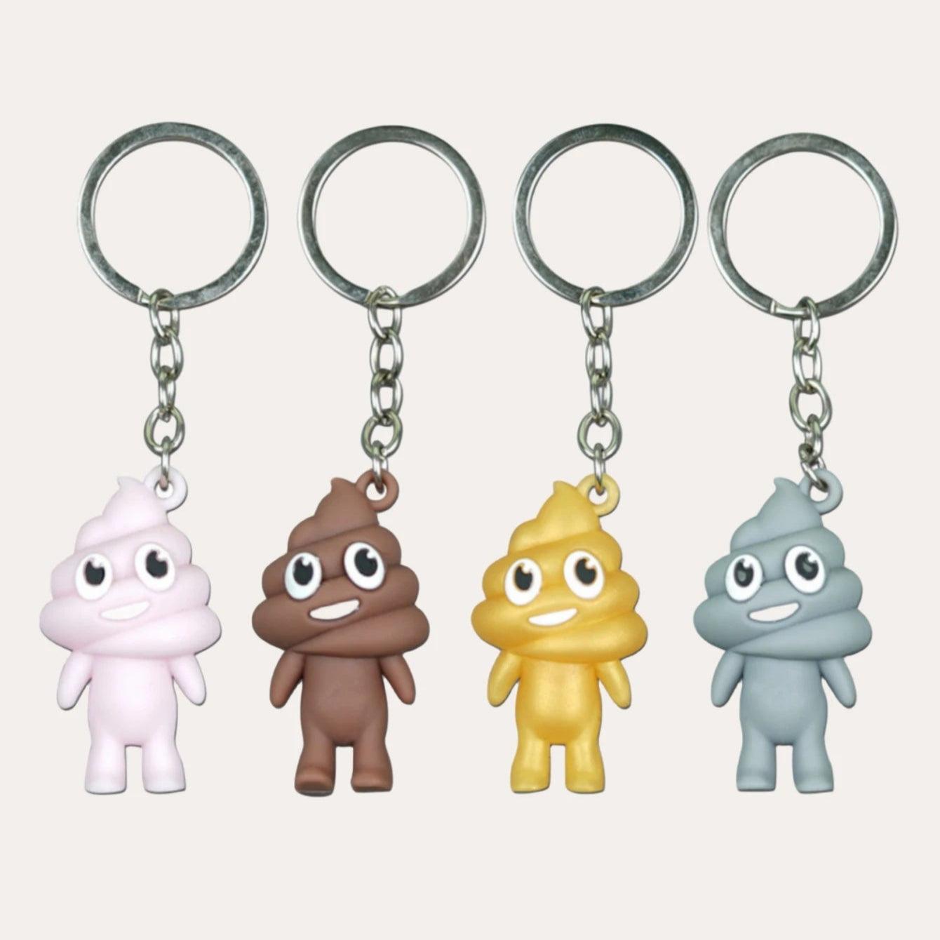 Four poop emoji keychains in pink, brown, yellow, and gray, each smiling, on metal keyrings.
