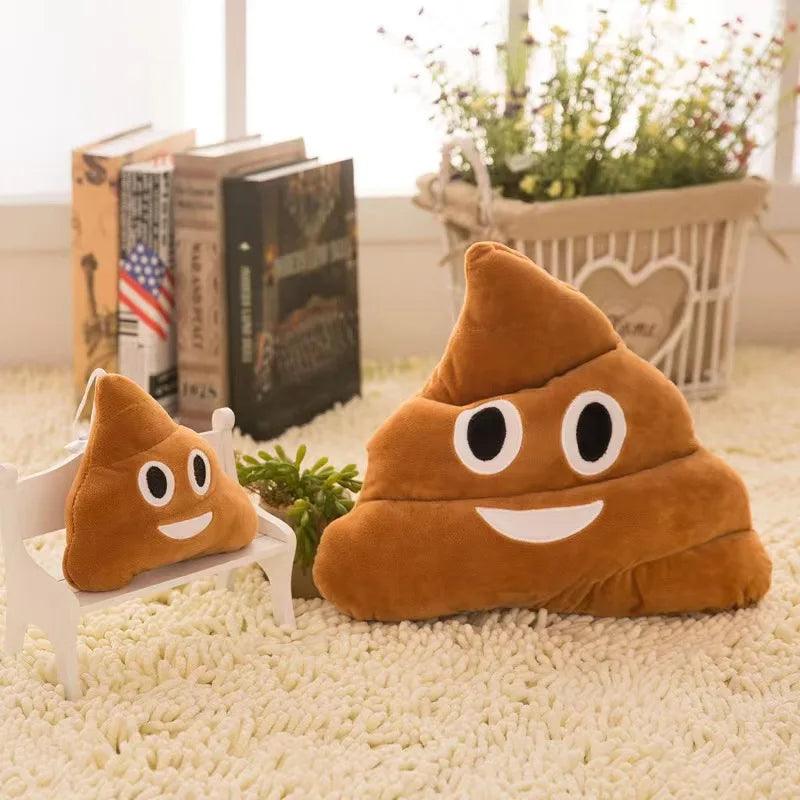 Large and small happy poop pillows, brown and smiling, on a carpet with plants.