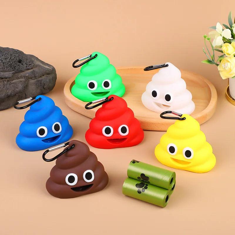 Six poop emoji poop bag dispensers in blue, brown, red, white, yellow, and green, with rolls on a wooden tray with flowers.