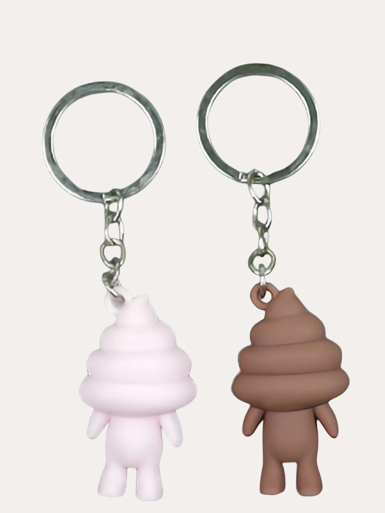 Pink and brown poop emoji keychains with smiling faces on metal keyrings, against a plain background.