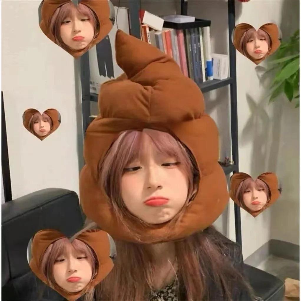 Person in a poop emoji head cover with heart frames, brown plush hat in a room