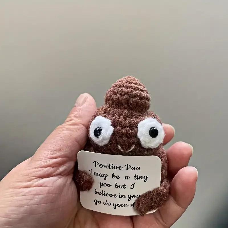 Hand holding a small Positive Poop plush with a sign, cute brown motivational toy.