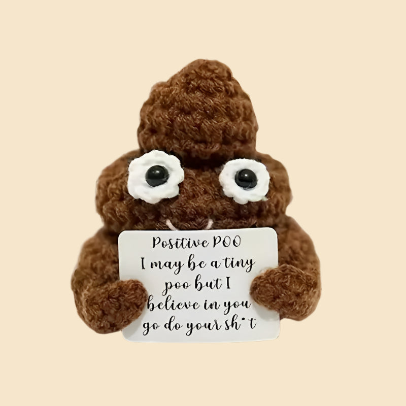 Brown Positive Poop plush holding a sign with an encouraging message on a wooden floor.