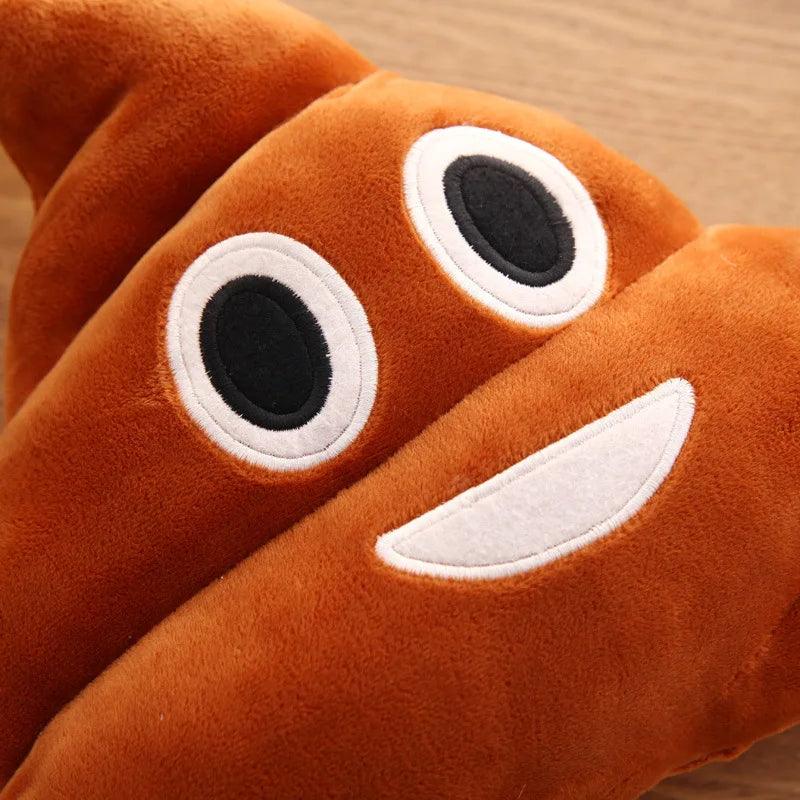 Close-up of smiling poop emoji pillow, brown with happy face, on a wood table.