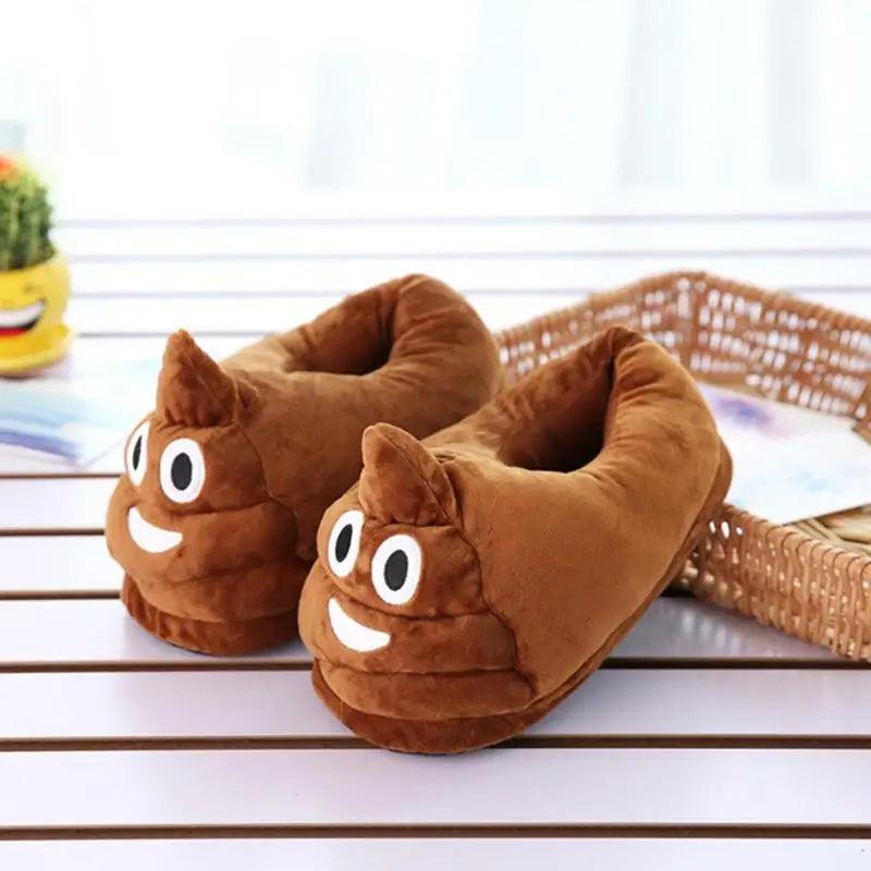 Pair of brown poop emoji slippers with smiling faces on a wooden table with a basket.